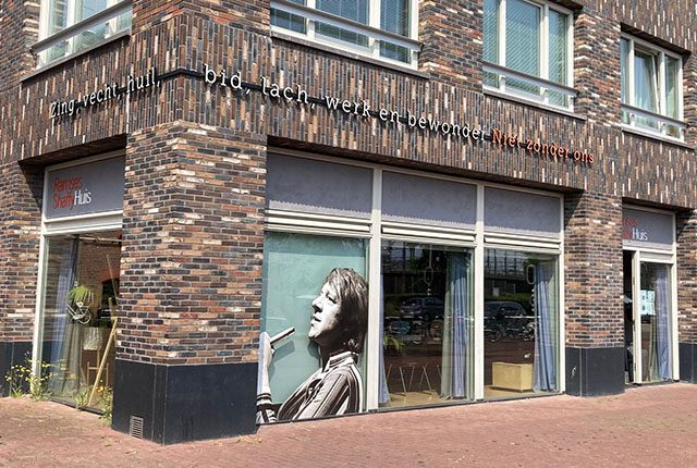 The facade of the Ramses Shaffy House with a mural and the text 'Zing, vecht, huil, bid, lach, werk en bewonder'