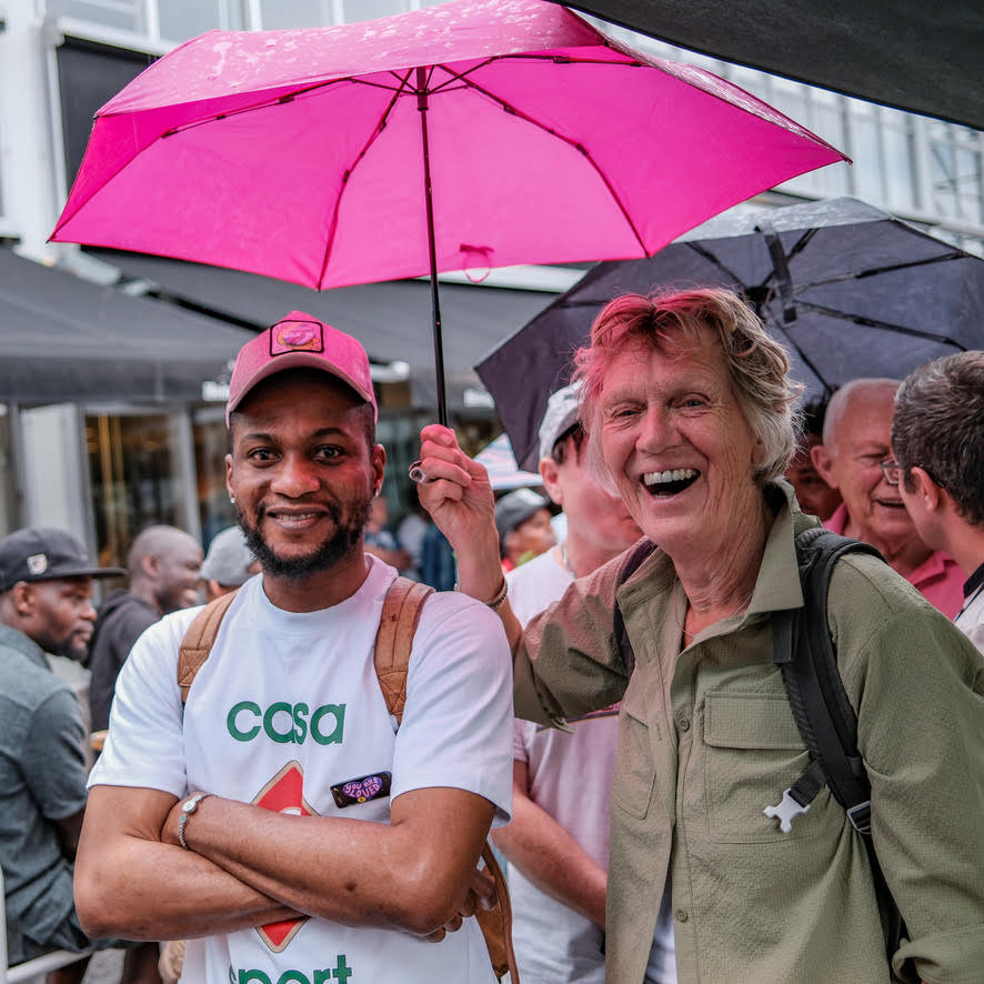 Mensen met een felroze paraplu op een drukke, vrolijke bijeenkomst